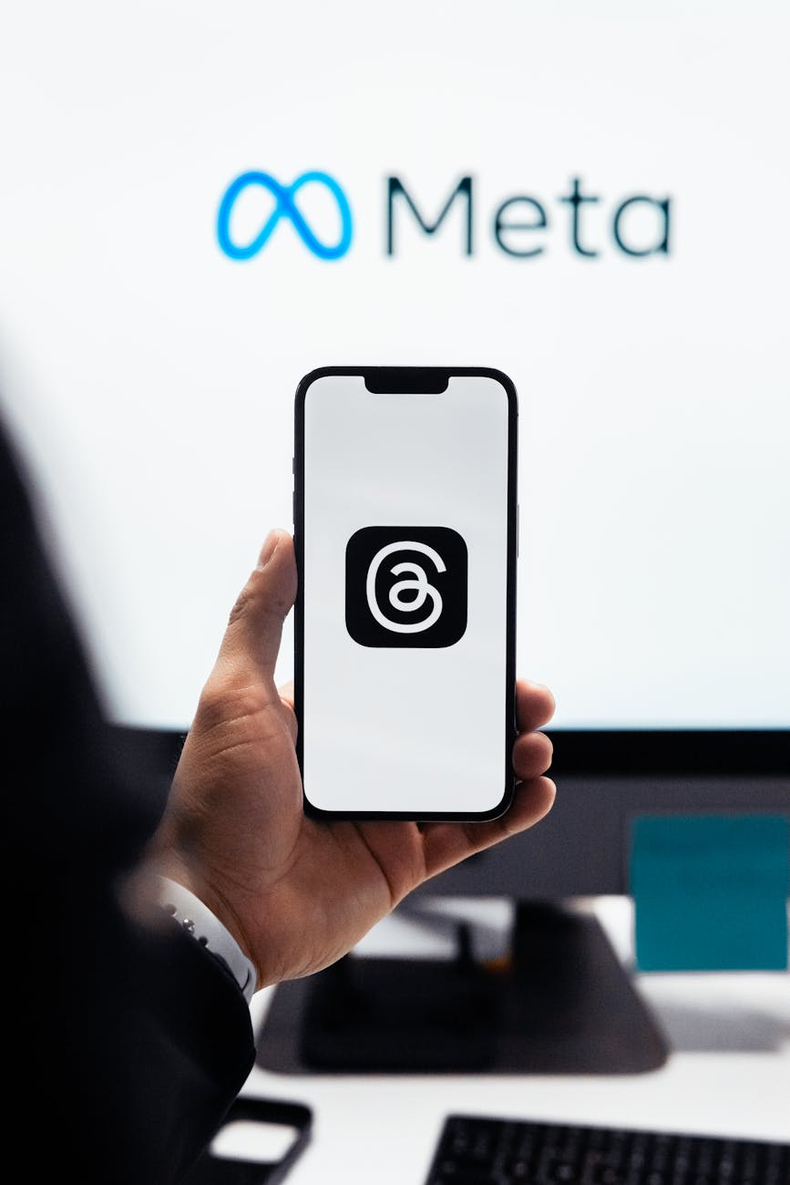 close up of a man holding a smartphone displaying the logo of the threads app