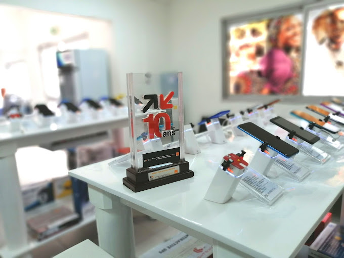 Smartphones, TV, électroménager… comment Glotelho veut démocratiser les bons plans au Cameroun à l'heure de la guerre des prix 61 Vue intérieure de l’agence Glotelho de Drouot à Akwa, avec des smartphones exposés sur des présentoirs et un trophée commémorant les 10 ans de l’entreprise.