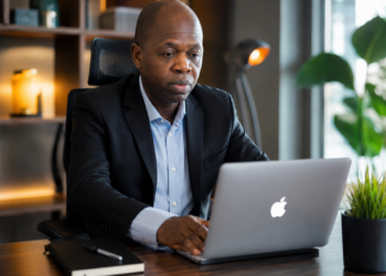 Portrait réaliste de Jonathan Chafeh, PDG de GLOTELHO, travaillant sur un ordinateur portable dans un bureau moderne, symbole de l'innovation et de l'entrepreneuriat numérique au Cameroun.