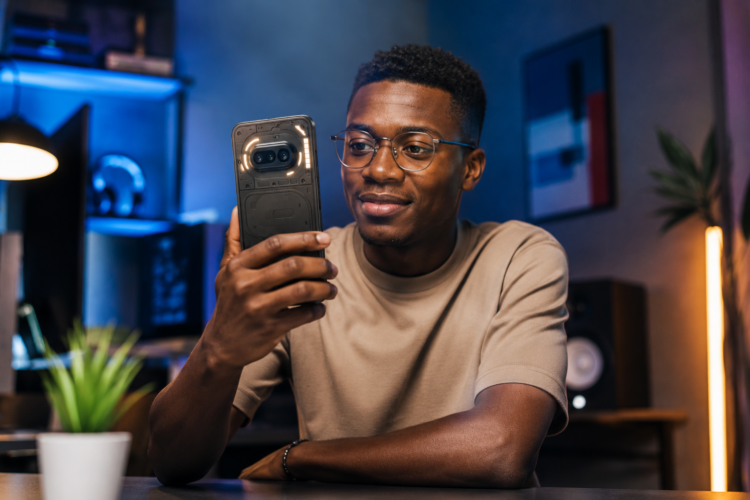 Nothing Phone (4a) : à 449,95 €, ce smartphone Android haut de milieu de gamme pourrait être l'un des meilleurs achats de 2026 61 Jeune homme africain utilisant un Nothing Phone (4a) dans un environnement high-tech moderne, avec éclairage cinématique et design transparent caractéristique du smartphone.