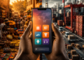 Des mains africaines tiennent un smartphone au centre d'une scène opposant un marché traditionnel africain à une zone logistique industrielle moderne, illustrant les transformations du commerce numérique.