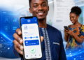 eBill fait peau neuve : au-delà du design, CAMTEL joue sa crédibilité numérique 73 Jeune homme africain présentant un smartphone affichant une interface de paiement numérique inspirée d'eBill de CAMTEL, tandis qu'une femme consulte son téléphone en arrière-plan dans un environnement technologique moderne.