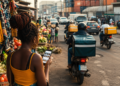 Pourquoi les géants du e-commerce échouent-ils en Afrique ? Les leçons du Cameroun, du Nigeria et du Kenya 72 Une consommatrice camerounaise consulte une application de commerce électronique sur son smartphone près d'un marché local animé, tandis que des motos de livraison circulent dans une rue urbaine évoquant les défis logistiques du e-commerce en Afrique.