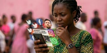 Une jeune femme camerounaise pensive regarde son smartphone, entourée d'icônes de réseaux sociaux en lévitation affichant un démenti sur la mort du père de Lionel Messi avec le portrait du joueur.
