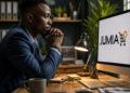 Professionnel africain observant le logo Jumia sur un écran d'ordinateur dans un bureau moderne, illustrant les enjeux du commerce électronique en Afrique.