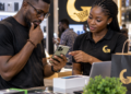 Client africain examinant un smartphone avec une conseillère dans une boutique Glotelho au Cameroun
