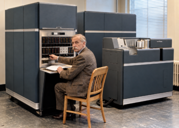 Jacques Perret assis devant un ordinateur IBM 650 dans une salle informatique des années 1950