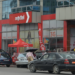 Façade d’un bâtiment aux couleurs de Nexttel Cameroun, avec l’enseigne de l’opérateur mobile, des véhicules stationnés et des installations commerciales.