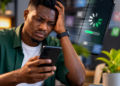 Un jeune homme africain utilise un smartphone Android lent affichant un chargement prolongé