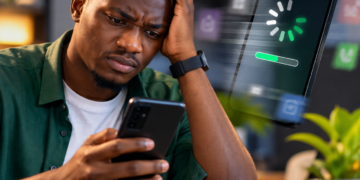 Un jeune homme africain utilise un smartphone Android lent affichant un chargement prolongé